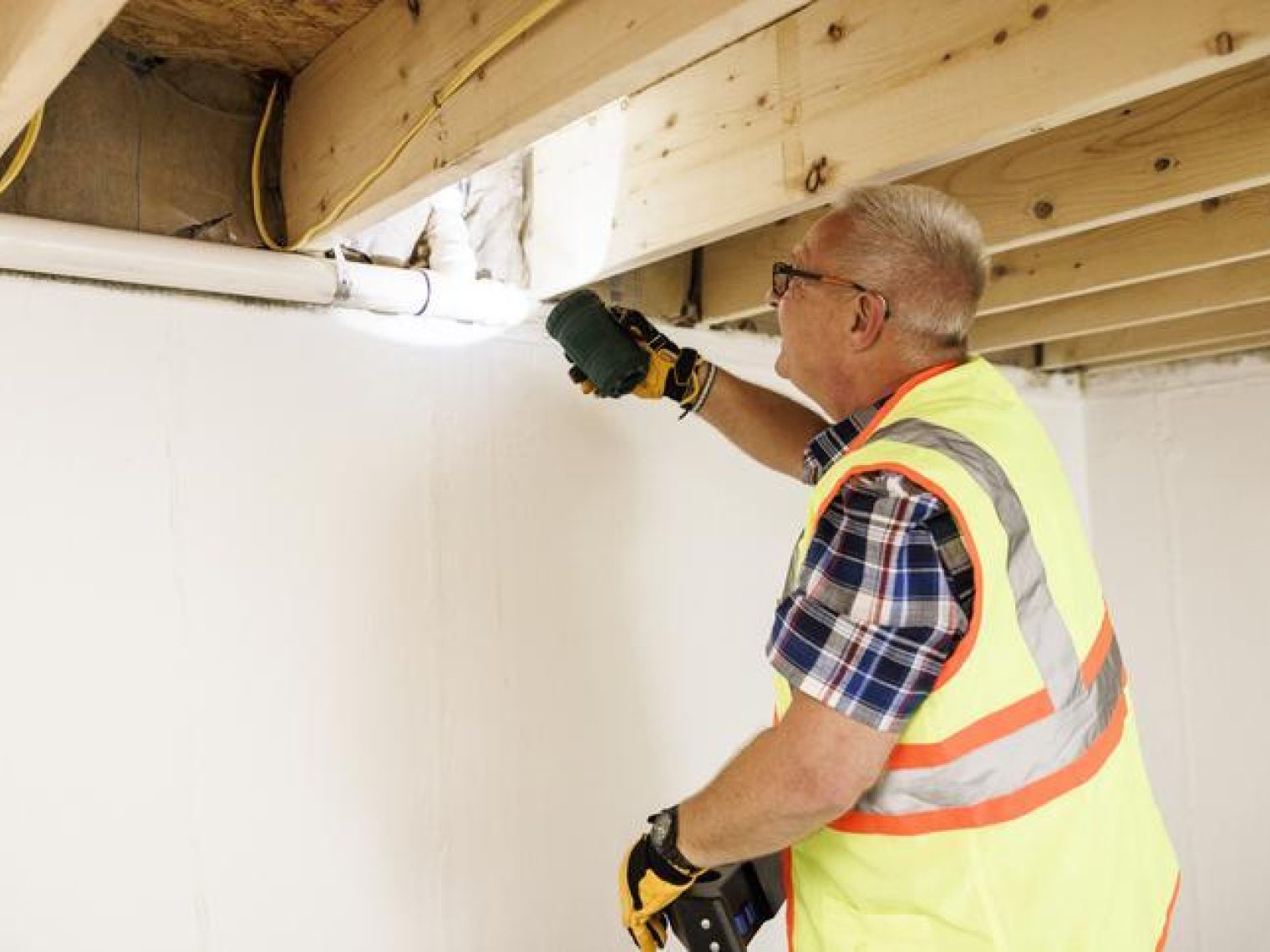 A man inspecting a home wearing protective gear.