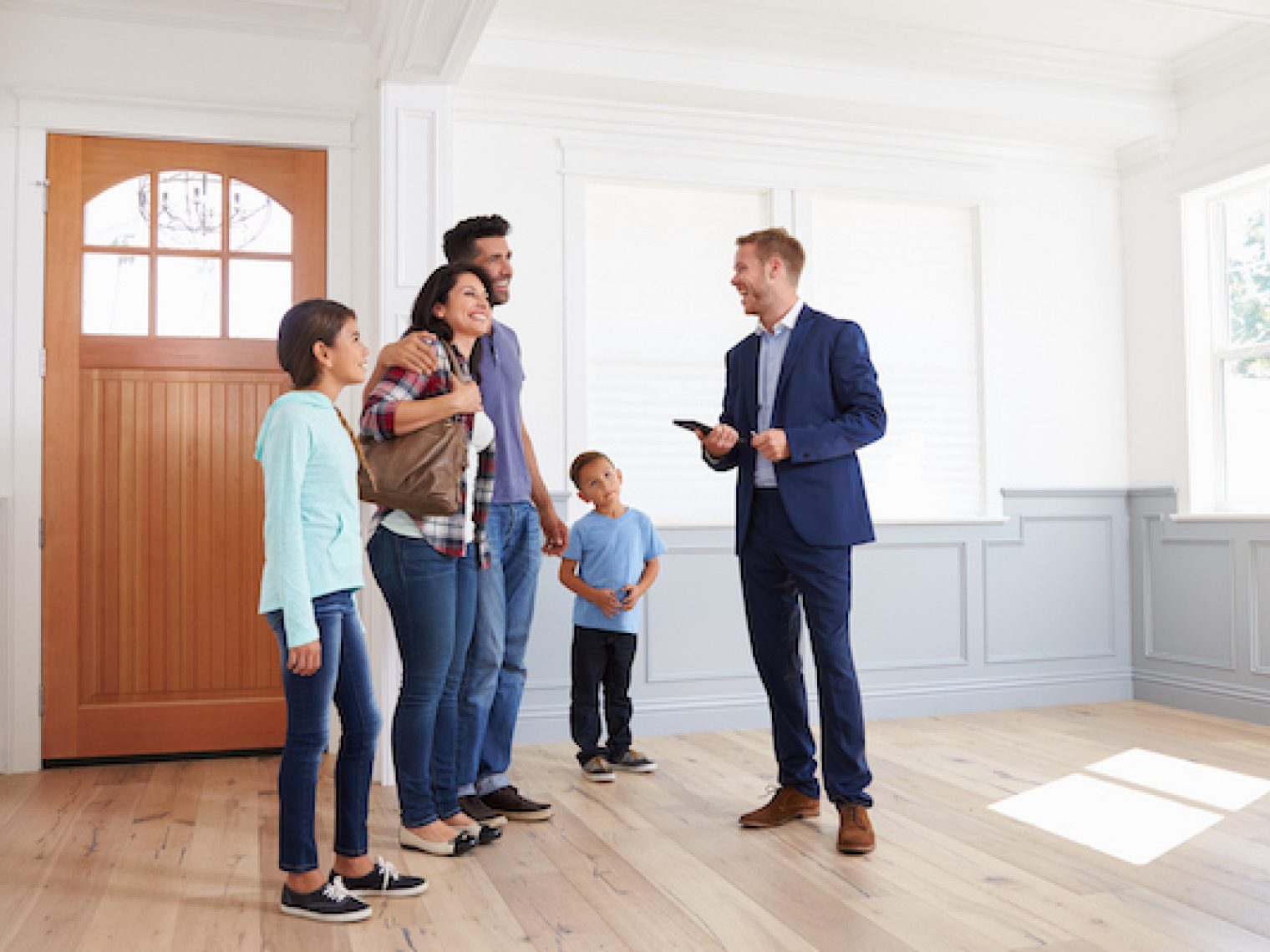 A real estate agent showing a family a brightly lit home.