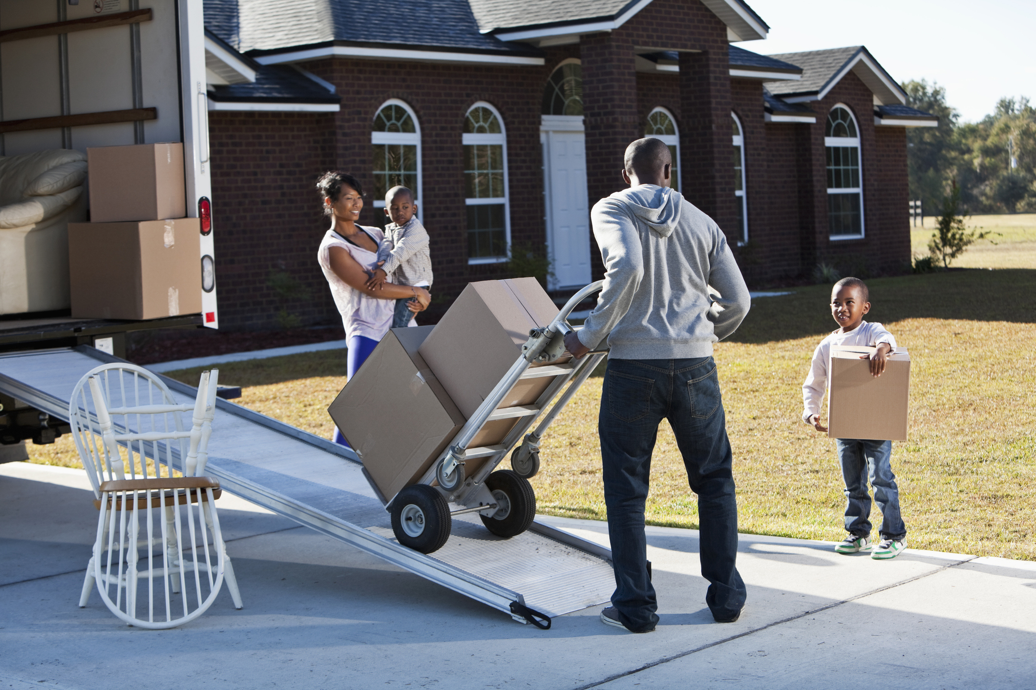 African American family moving boxes from home into vehicle.