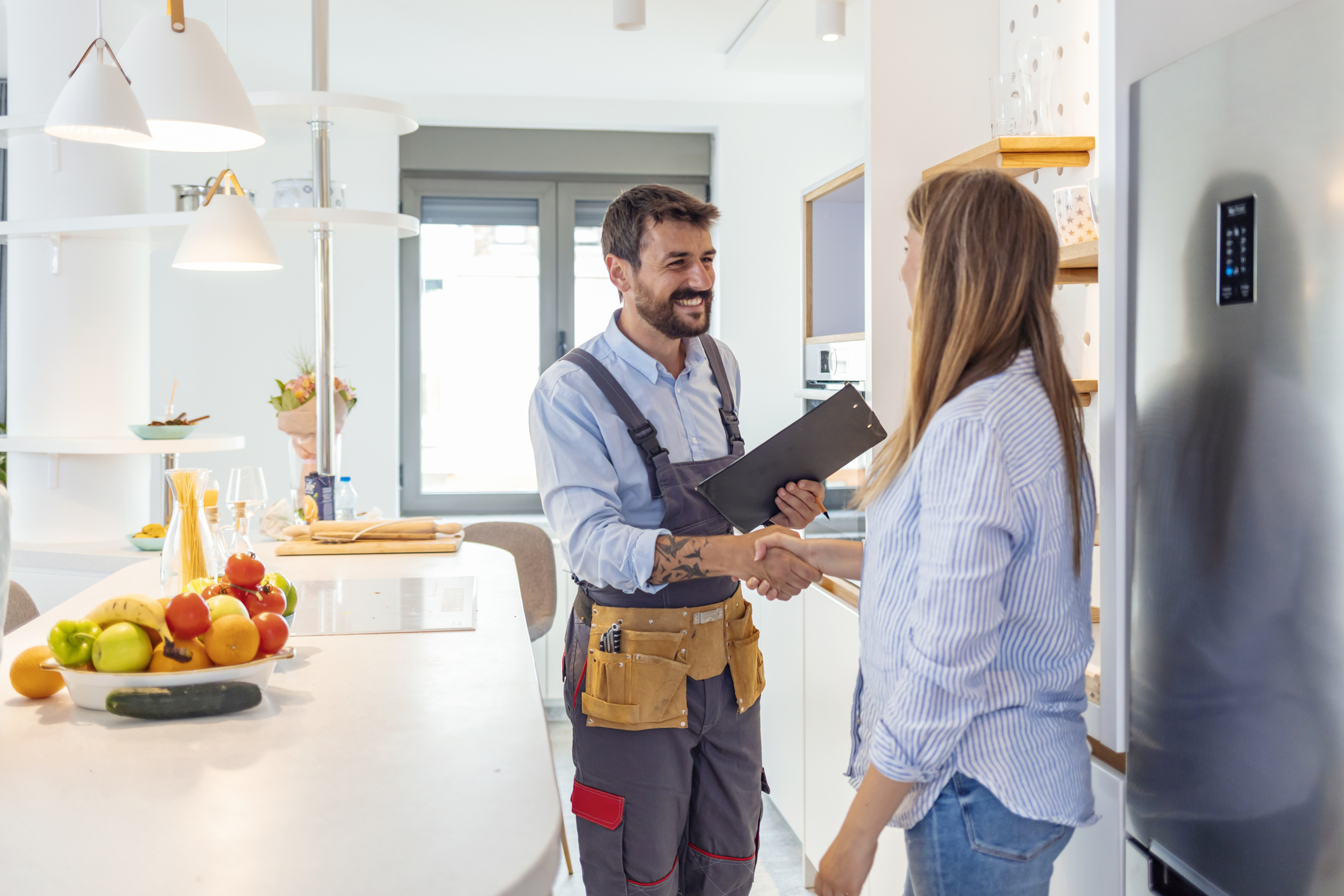 Young woman shaking hands to male inspector with clipboard in the kitchen.