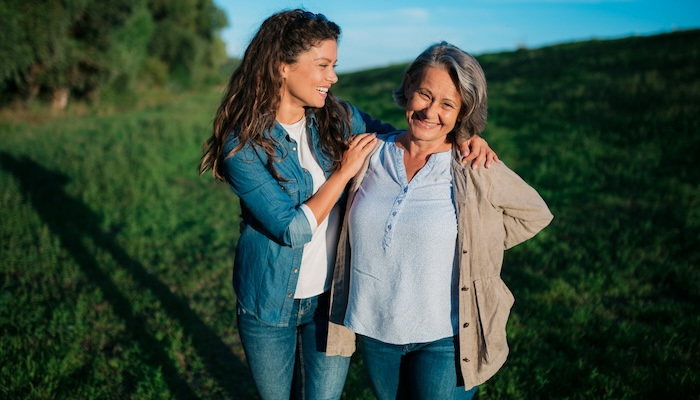 Happy mother and daughter standing outdoors.