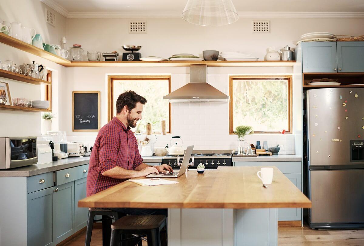 Man working on laptop on kitchen island.